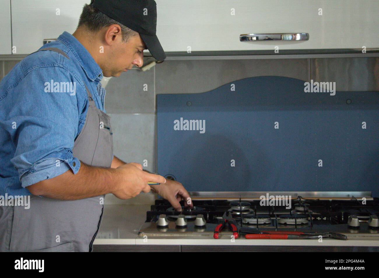 image-of-a-handyman-technician-who-with-a-detector-carries-out-checks-in-a-kitchen-for-safety-and-gas-leaks-from-the-stove-2PG4M4A.jpg