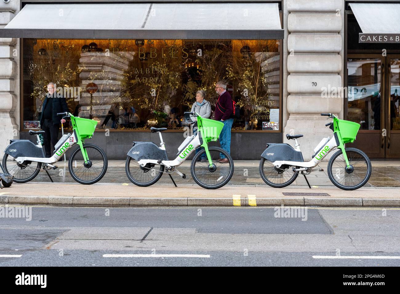 Lime electric hire bike scheme bicycles left outside Cakes & Bubbles shop in Regent Street. Dockless hire bicycles left on pavement in tourist area Stock Photo