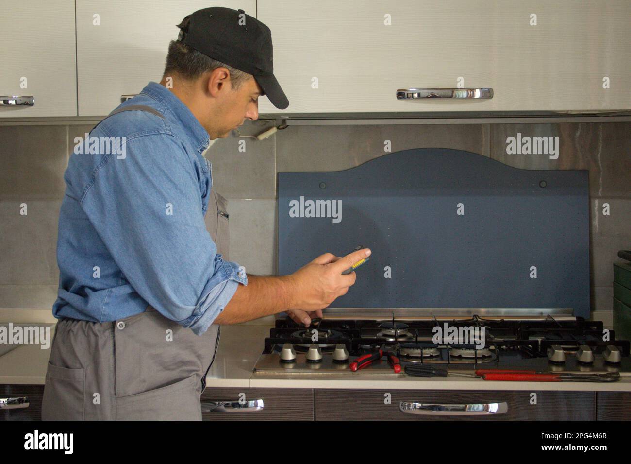 image-of-a-handyman-technician-who-with-a-detector-carries-out-checks-in-a-kitchen-for-safety-and-gas-leaks-from-the-stove-2PG4M6R.jpg