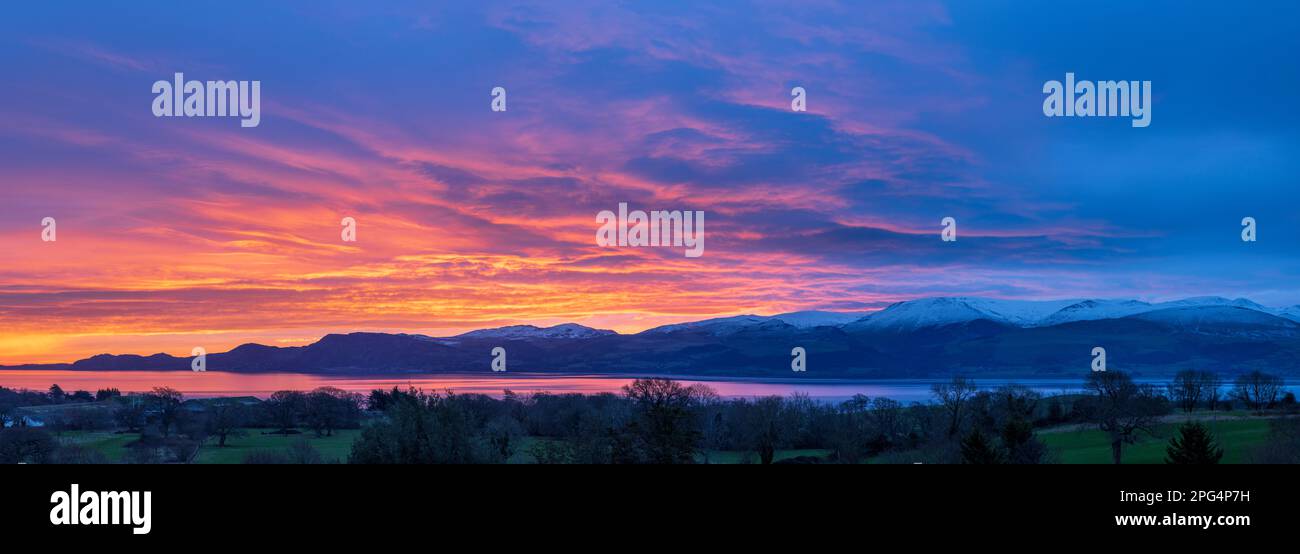 Sunrise over the snow covered Snowdonia mountains across the Menai Strait near Beaumaris, Anglesey, North Wales Stock Photo