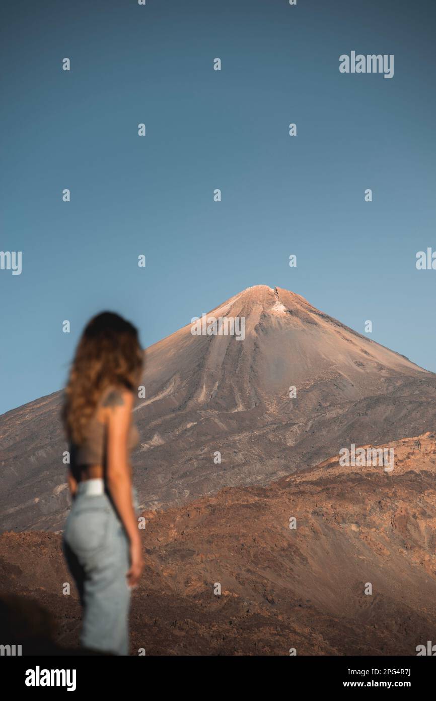 Chica no reconocible paseando por el parque nacional de las cañadas del Teide al atardecer. El pico Teide al fondo. Stock Photo