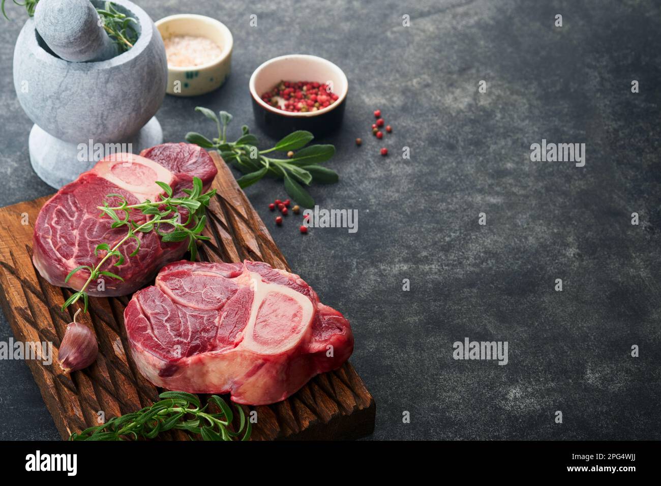 Osso Buco raw steak meat. Barbecue meat. Raw fresh cross cut veal shank and seasonings pepper, rosemary, thyme and salt on old wooden rustic backgroun Stock Photo