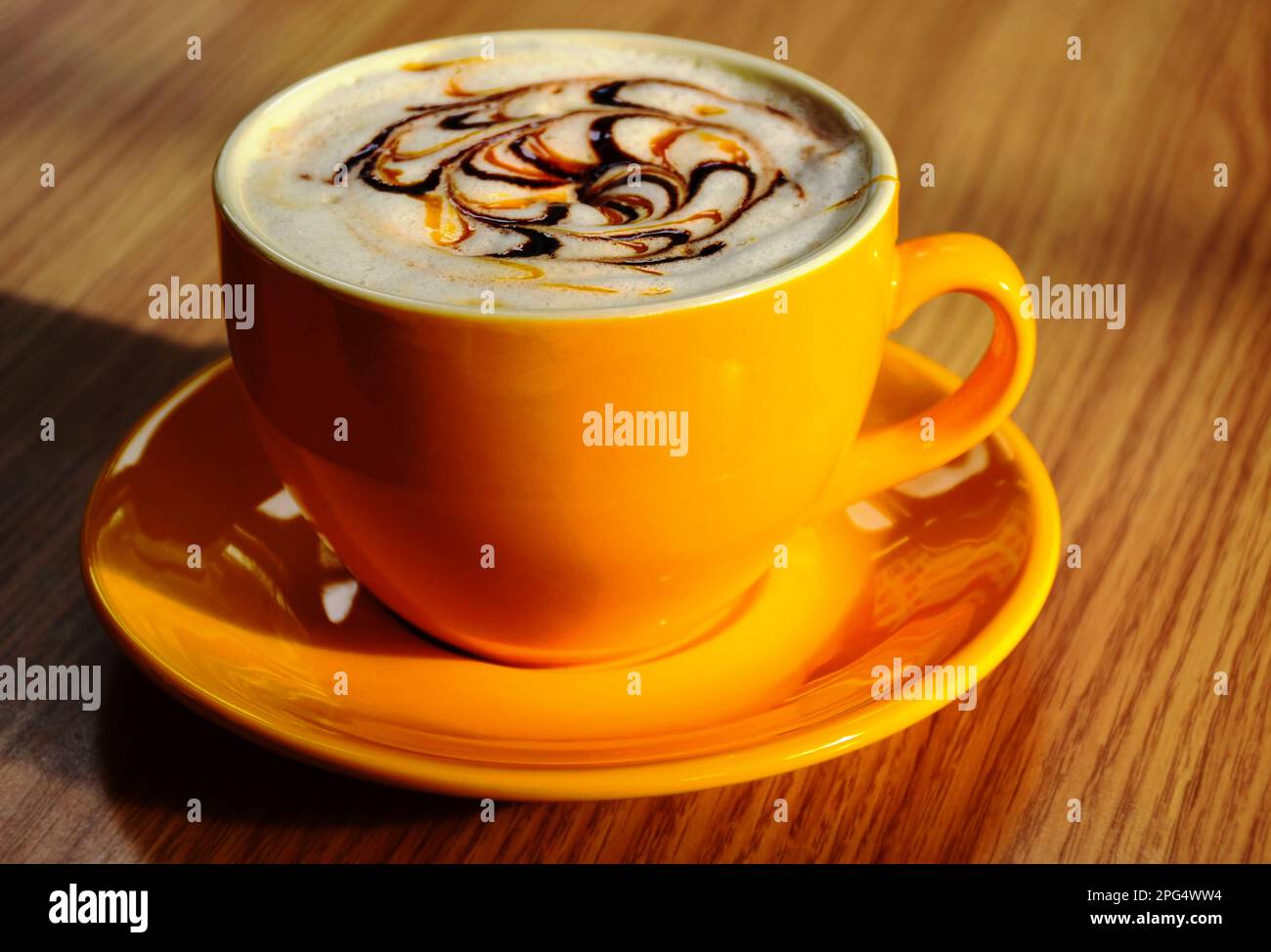 yellow porcelain cappuccino cup or mug in closeup view. shiny reflective surface. decorative white froth. chocolate pattern. tasty hot coffee concept. Stock Photo