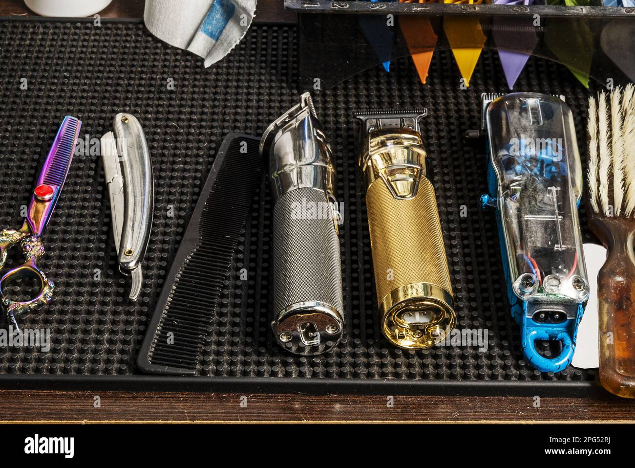 A few different hair clippers, blades, combs and razors on a black ...