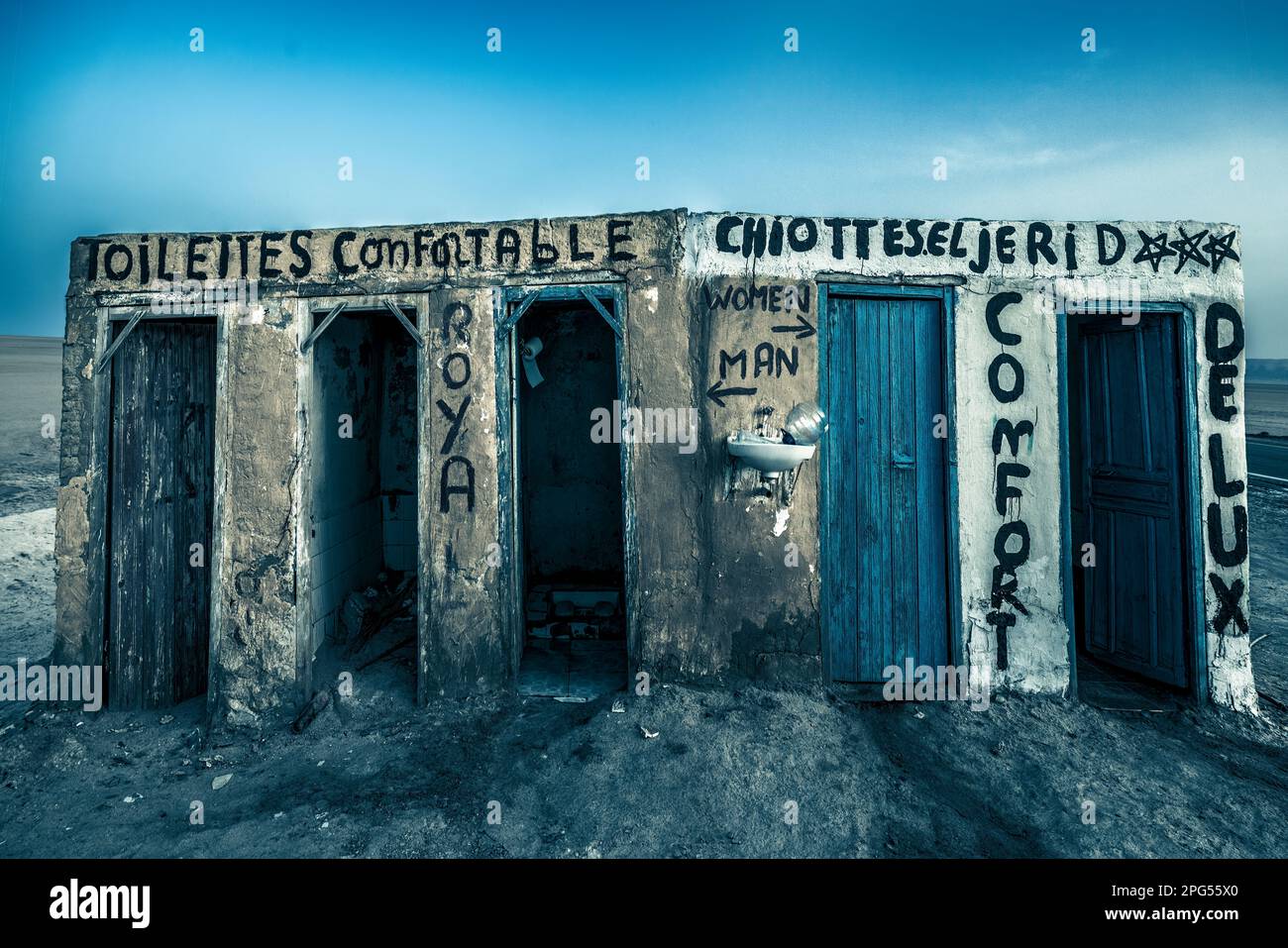 This haunting photograph captures the stark contrast between the decrepit state of a restroom in the Tunisian desert and the luxurious descriptions sc Stock Photo