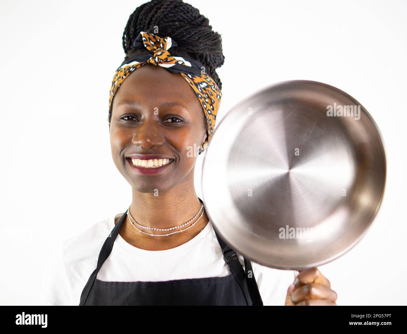 Young female chef showing a stainless pan while smiling and looking at ...