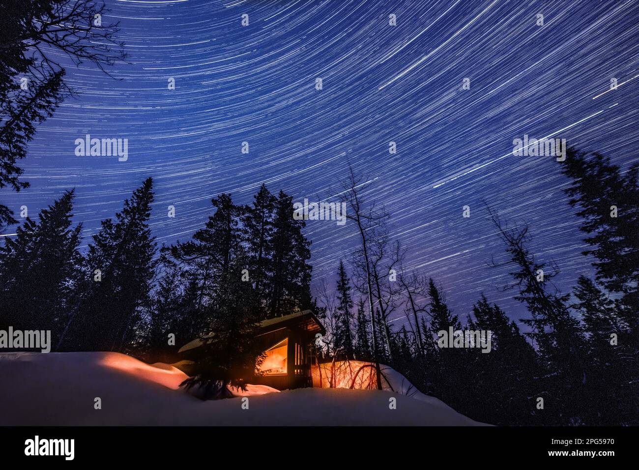 A startrail above a remote cabin in the snow in a forest in Norway Stock Photo