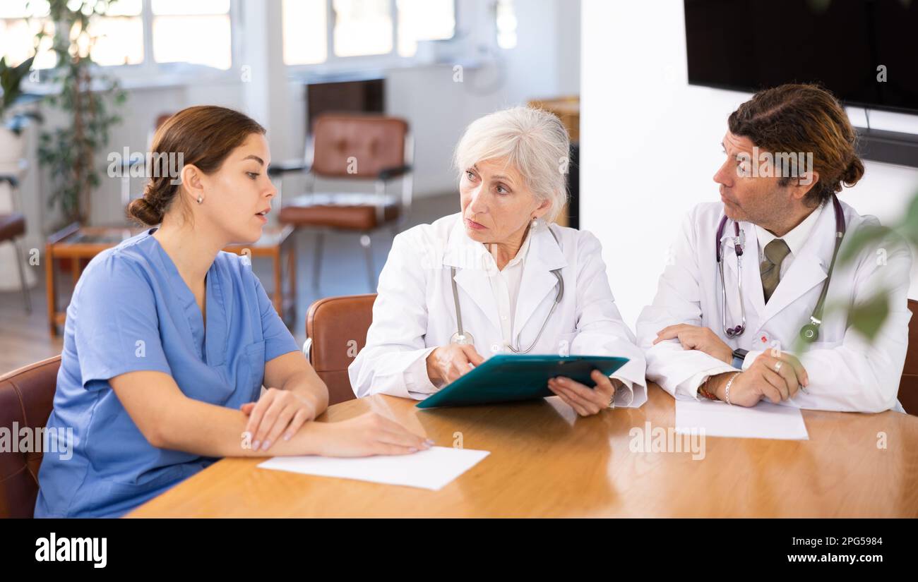 Group of professional doctors sitting at table and discussing diagnosis and treatment of patients during medical council Stock Photo
