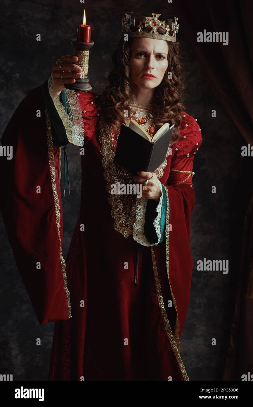 Full length portrait of medieval queen in red dress with book, candle ...