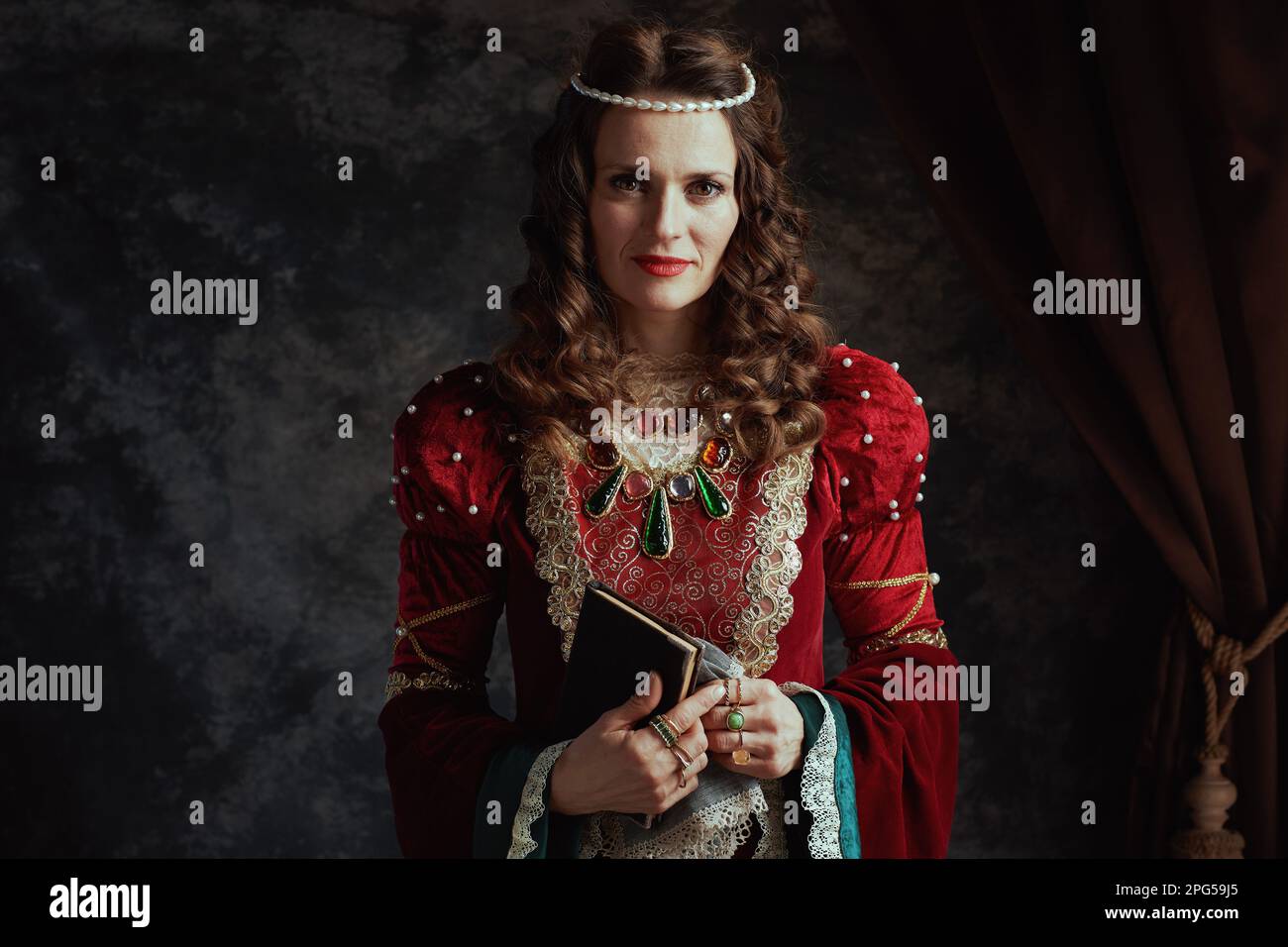 medieval queen in red dress with book and handkerchief on dark gray ...