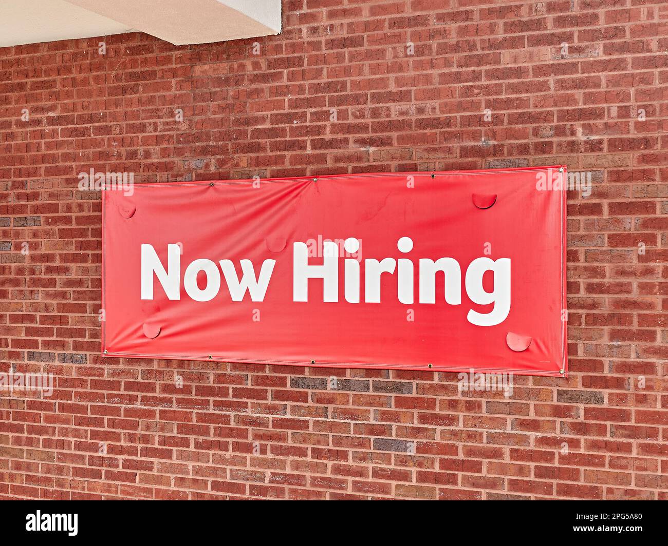 Generic now hiring sign, meaning help wanted, on the side of a business in Montgomery Alabama, USA. Stock Photo