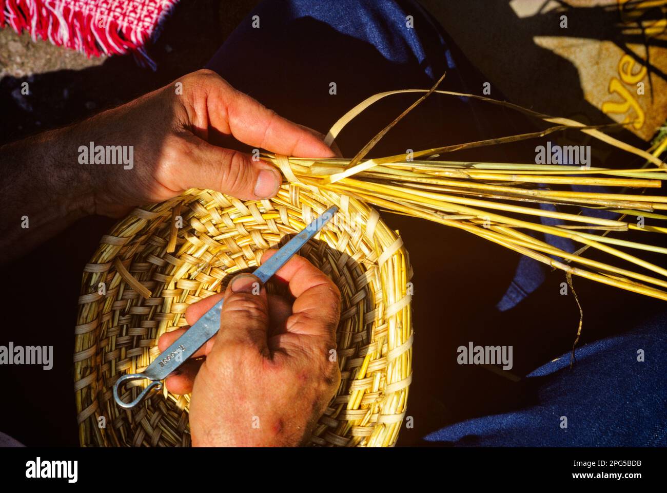 1980s BASKET WEAVING HANDS USING A METALTOOL WHILE WEAVING REEDS AND ...