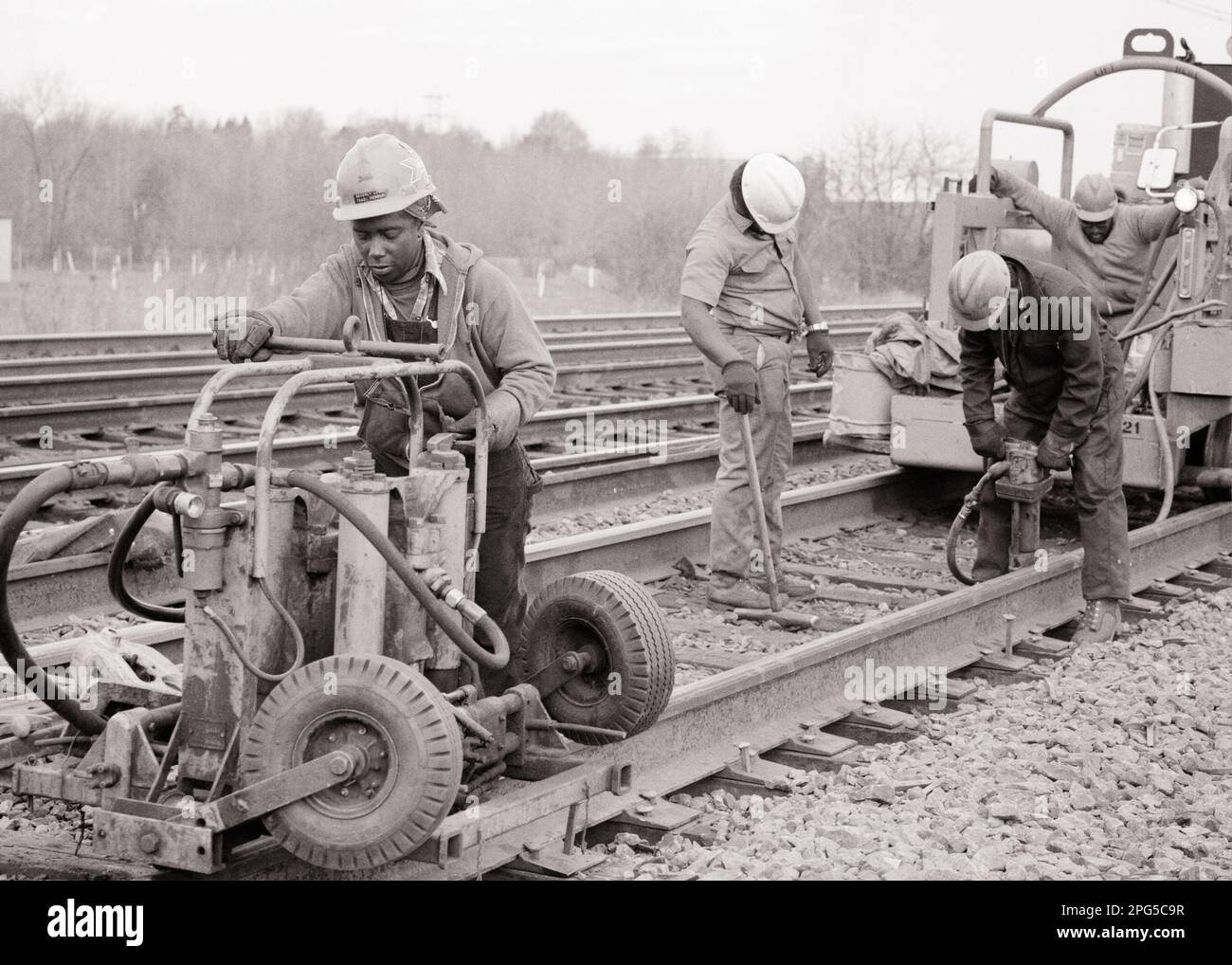 1970s FOUR AFRICAN AMERICAN RAILROAD WORKERS BOTH MALE AND FEMALE DOING RAIL REPAIR ON AMTRAK TRAIN TRACKS - i6921 HAR001 HARS CONFIDENCE TRANSPORTATION B&W TRACKS RAIL SKILL OCCUPATION SKILLS AFRICAN-AMERICANS AFRICAN-AMERICAN AND CAREERS BLACK ETHNICITY LABOR PRIDE OPPORTUNITY EMPLOYMENT OCCUPATIONS MAINTENANCE INFRASTRUCTURE RAILROADS EMPLOYEE COOPERATION GENDER MID-ADULT MID-ADULT MAN PRECISION YOUNG ADULT MAN YOUNG ADULT WOMAN BLACK AND WHITE HAR001 LABORING OLD FASHIONED AFRICAN AMERICANS Stock Photo