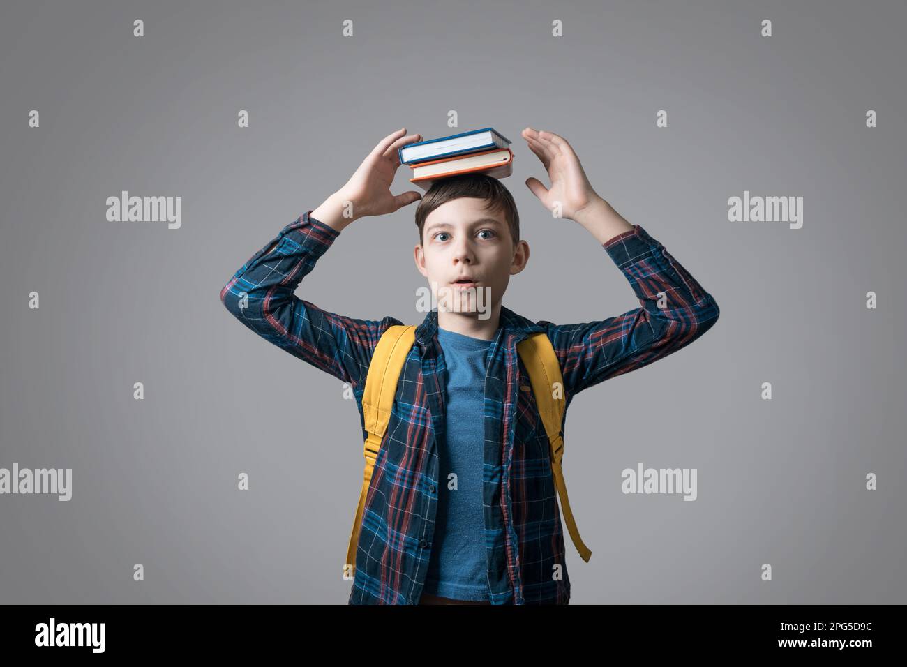 school boy holding stack of books on head on grey background Stock ...