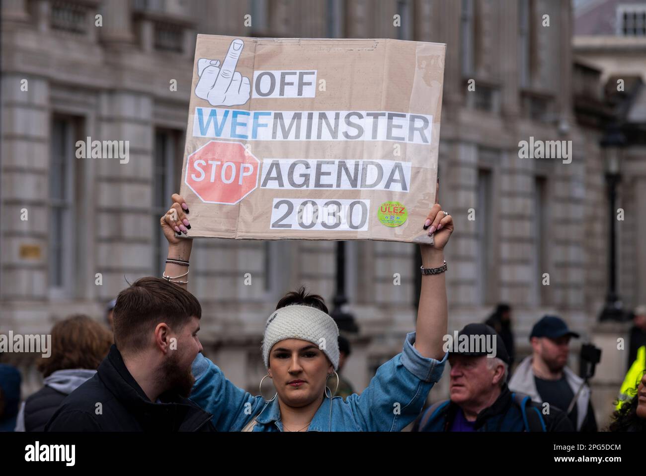 Protest against ULEZ zone expansion in London, UK. Female with placard stating * off WEFminster, stop agenda 2030. World Economic Forum society plans Stock Photo