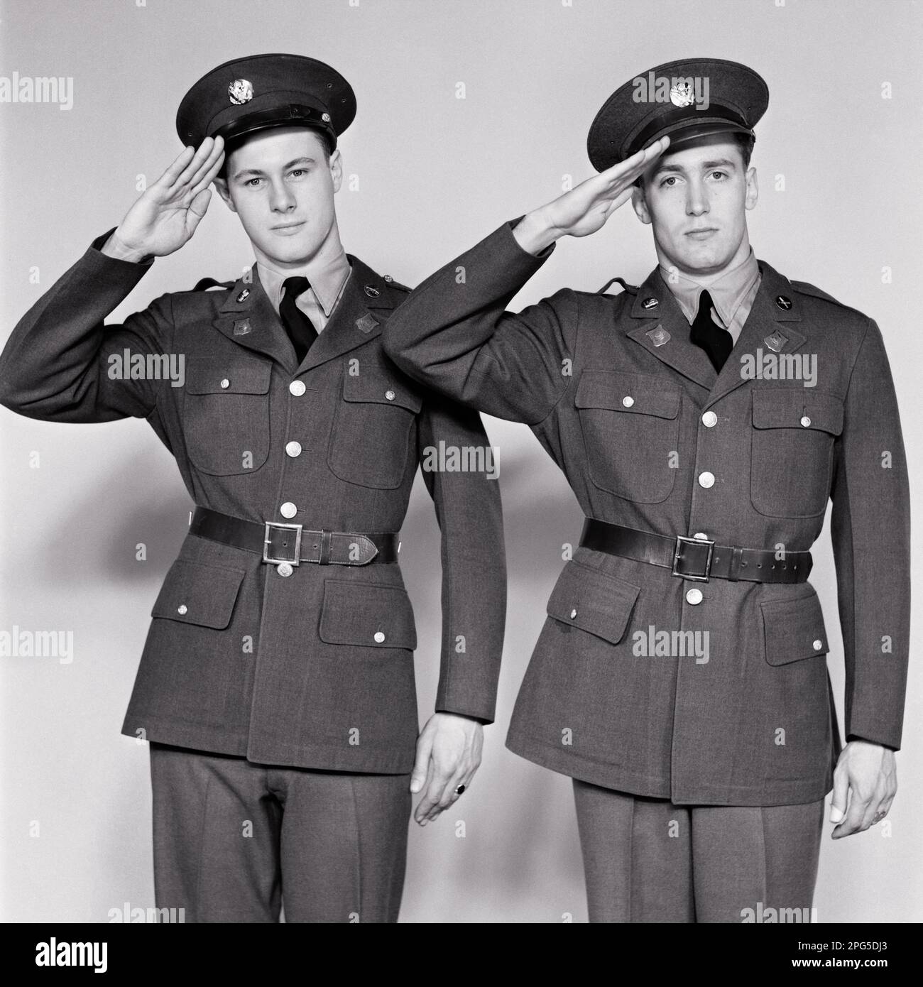 1940s TWO MEN IN ARMY UNIFORMS LOOKING AT CAMERA SALUTING JUST ENLISTED AT THE BEGINNING OF WORLD WAR 2 - m1324 HAR001 HARS B&W EYE CONTACT FREEDOM ADVENTURE SALUTE COURAGE LEADERSHIP PRIDE OPPORTUNITY OCCUPATIONS POLITICS SIBLING UNIFORMS SUPPORT COOPERATION MID-ADULT MID-ADULT MAN SALUTING TOGETHERNESS YOUNG ADULT MAN BEGINNING BLACK AND WHITE CAUCASIAN ETHNICITY ENLISTED HAR001 OLD FASHIONED Stock Photo