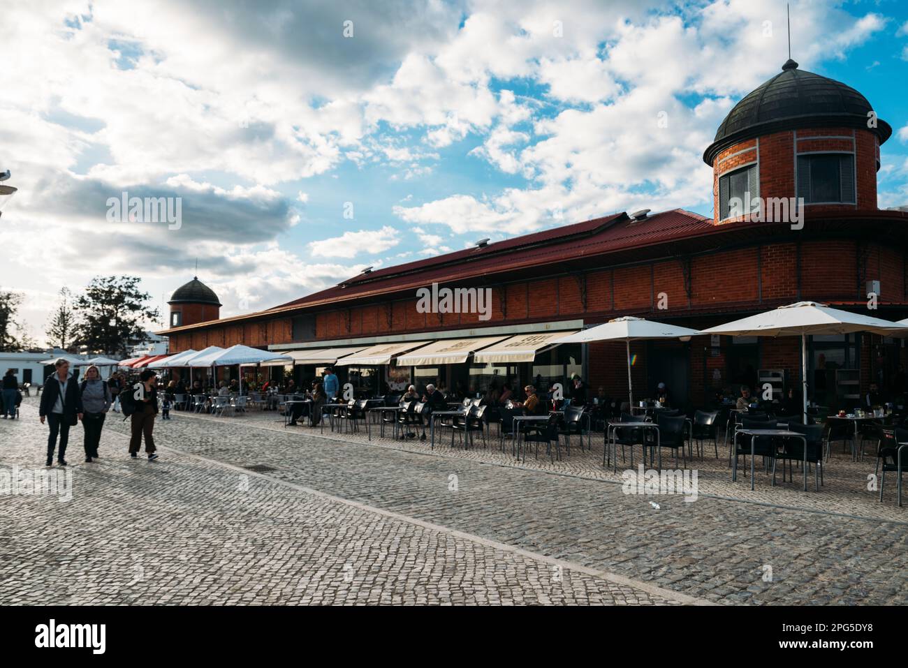 Olhao, Algarve, Portugal - March 18, 2023: Facade of the famous fish and produce market Olhao, East Algarve with tourists strolling by Stock Photo