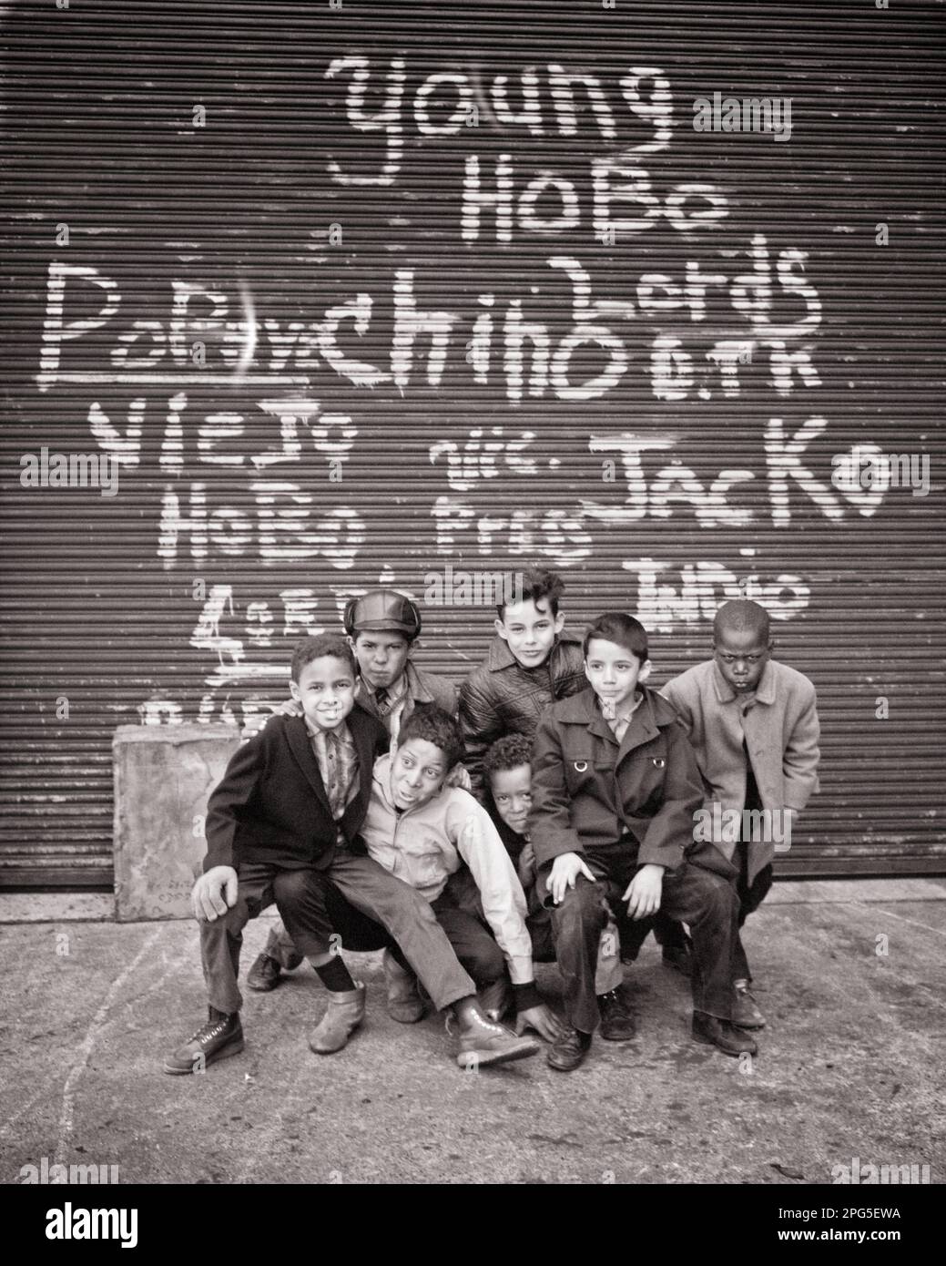 1970s GROUP OF HISPANIC AND AFRICAN AMERICAN BOYS POSED LOOKING AT CAMERA UNDER SOME GRAFFITI NEW YORK CITY NY USA - w5857 HAR001 HARS HALF-LENGTH UNITED STATES OF AMERICA MALES NY B&W EYE CONTACT HAPPINESS WELFARE AFRICAN-AMERICANS AFRICAN-AMERICAN AND RECREATION SEVEN BLACK ETHNICITY NAMES PRIDE NYC CONCEPTUAL NEW YORK 7 CITIES FRIENDLY SUPPORT NEW YORK CITY SOME TAGGING COOPERATION CREATIVITY GRAFFITI JUVENILES POSED PRE-TEEN PRE-TEEN BOY BLACK AND WHITE CAUCASIAN ETHNICITY HAR001 HISPANIC ETHNICITY IDENTITY OLD FASHIONED AFRICAN AMERICANS Stock Photo