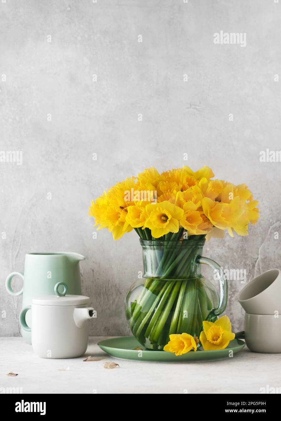 Beautiful spring floristic arrangement yellow daffodil flowers in a vintage glass jug. Homemade decoration for Easter or Mothers day. Copy space. Stock Photo