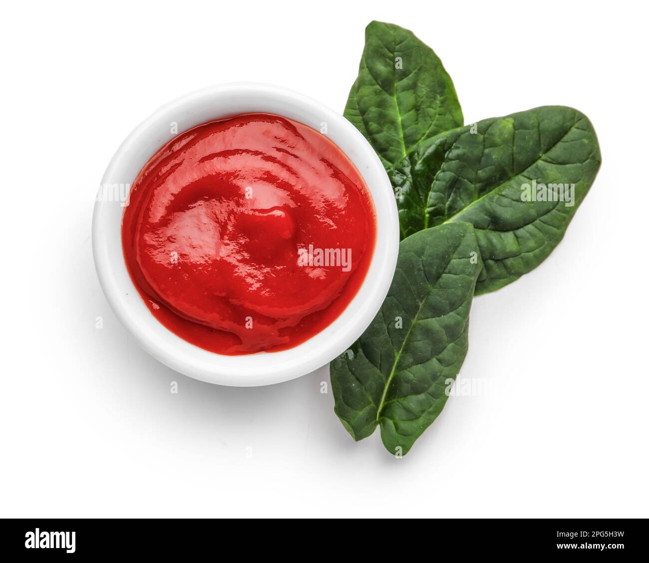 Bowl of tasty ketchup and spinach leaves isolated on white background