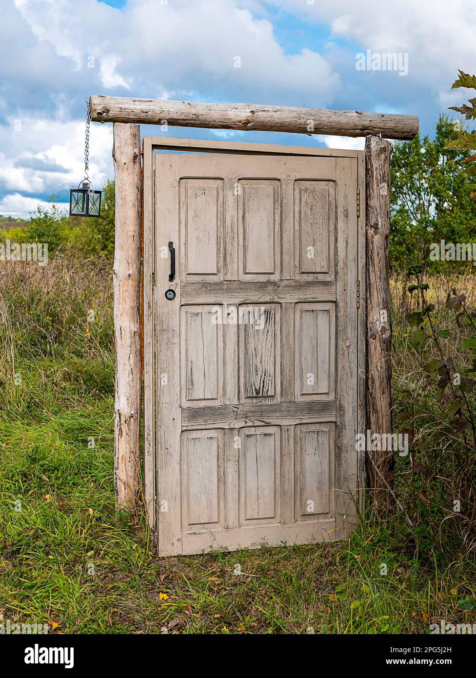 Wooden door without a house the middle of the field. Old doorway that leads to nowhere. Concept of mystery portal Stock Photo