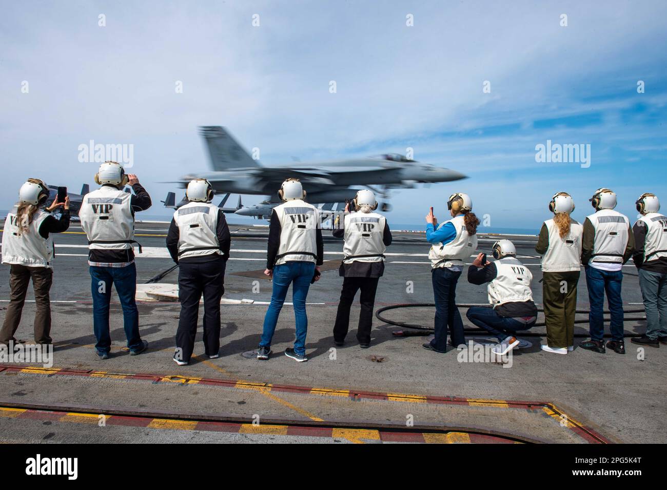 230318-N-PQ495-1056 PACIFIC OCEAN (March 18, 2023) Distinguished visitors observe an F/A-18E Super Hornet, assigned to the “Golden Dragons” Strike Fighter Squadron (VFA) 192, recover on the flight deck of Nimitz-class aircraft carrier USS Carl Vinson (CVN 70). Vinson is currently underway conducting routine maritime operations. (U.S. Navy photo by Mass Communication Specialist 3rd Class Larissa T. Dougherty) Stock Photo