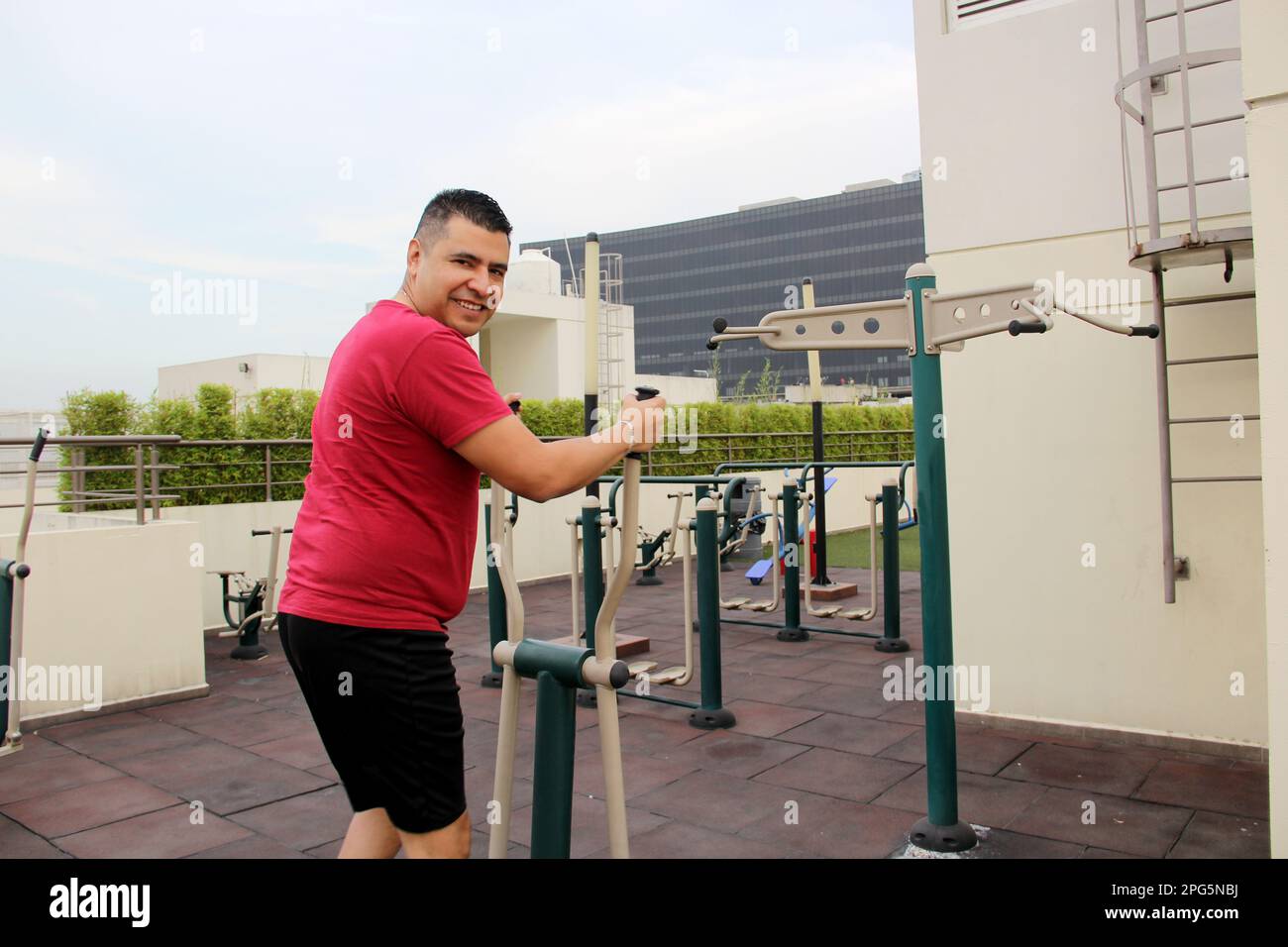 Adult 40yearold Latino man exercises on the roof garden of her