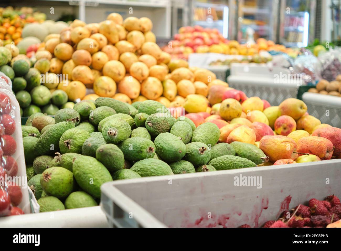 Piles of feijoas, apples and guavas in the fruit section of a market. Stock Photo