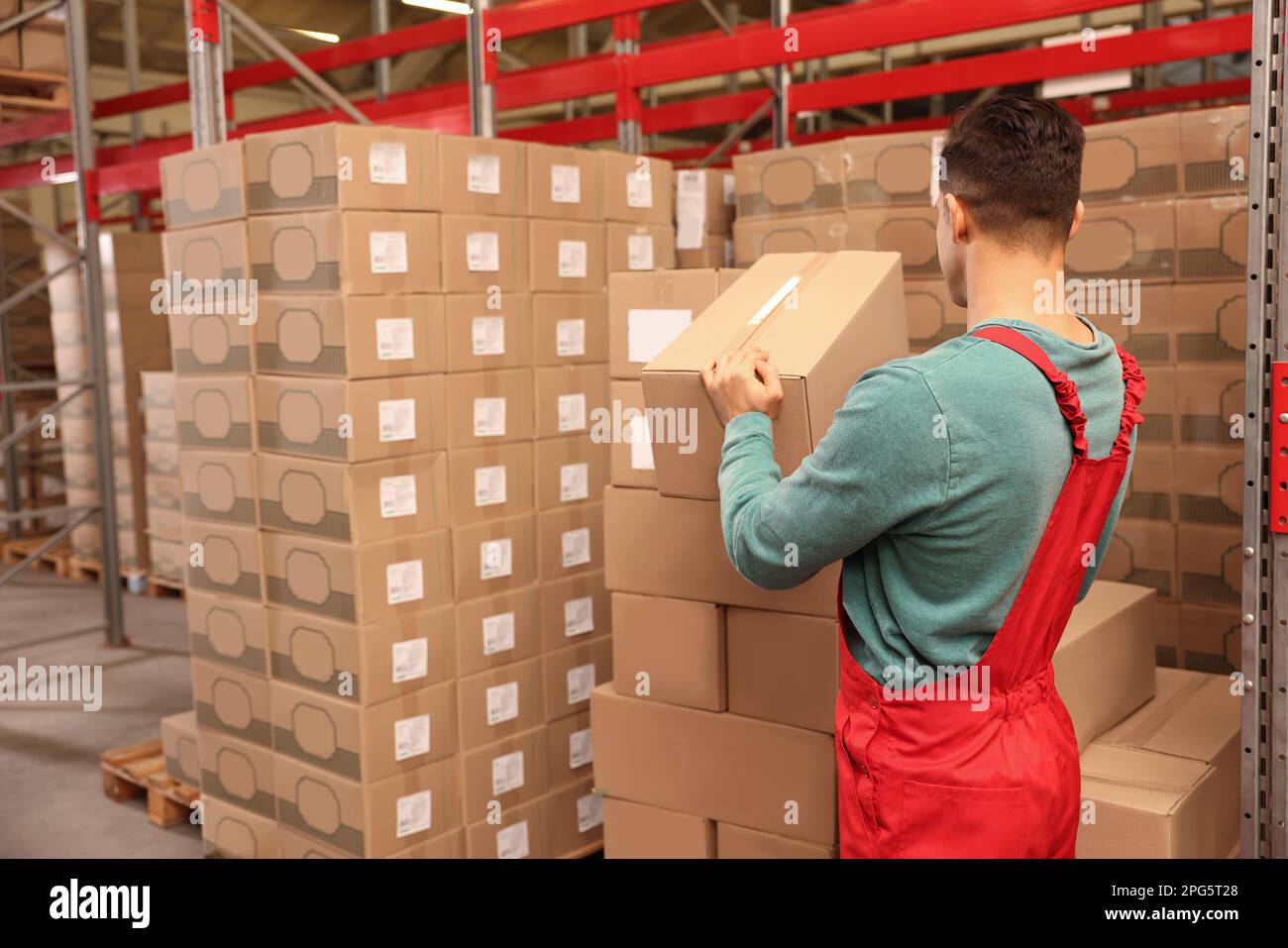Worker stacking cardboard boxes in warehouse. Wholesaling Stock Photo