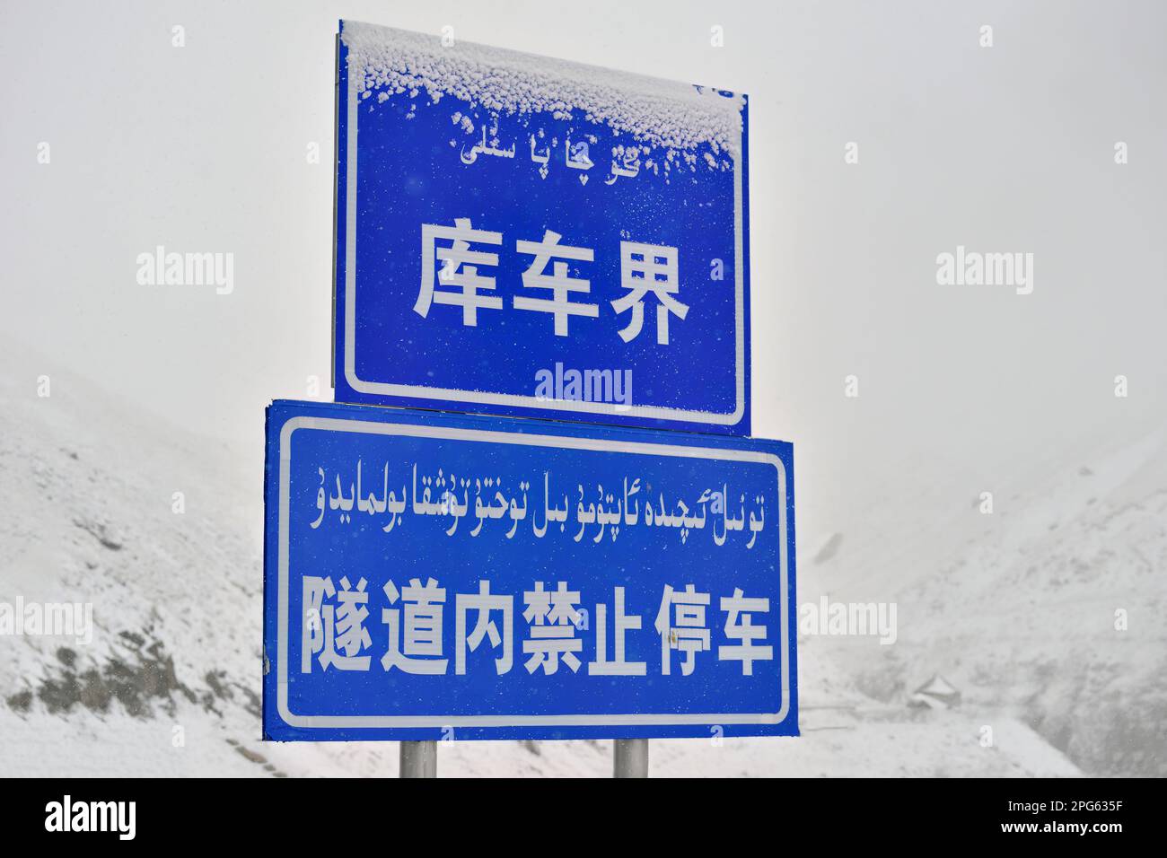 A road sign standing in the snow beside Duku Highway in Xinjiang Stock Photo