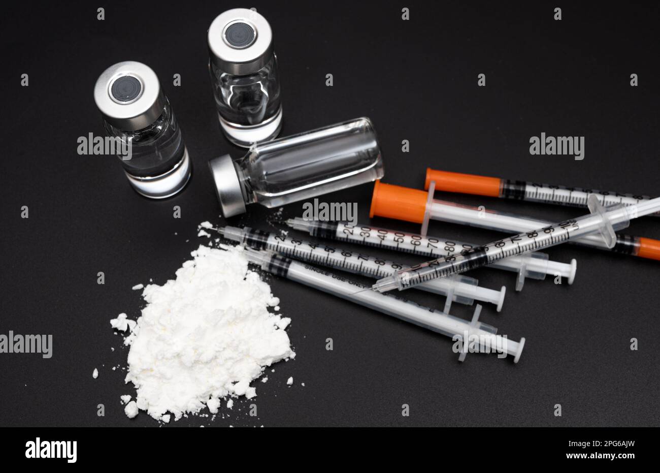 Drug crime concept with white powder and disposable syringe on black background Stock Photo