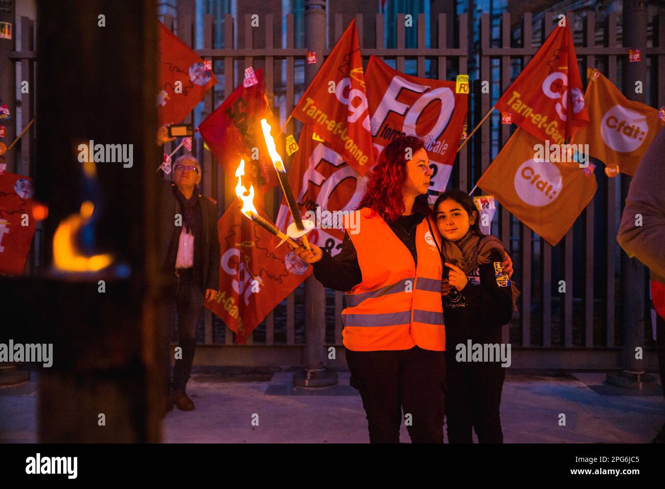 Montauban, France. 20th Mar, 2023. A CFDT activist and her city in front of  flags, cftd, fo, Cgt torches lit in hand. Operation punch in front of the  prefecture of 82, the