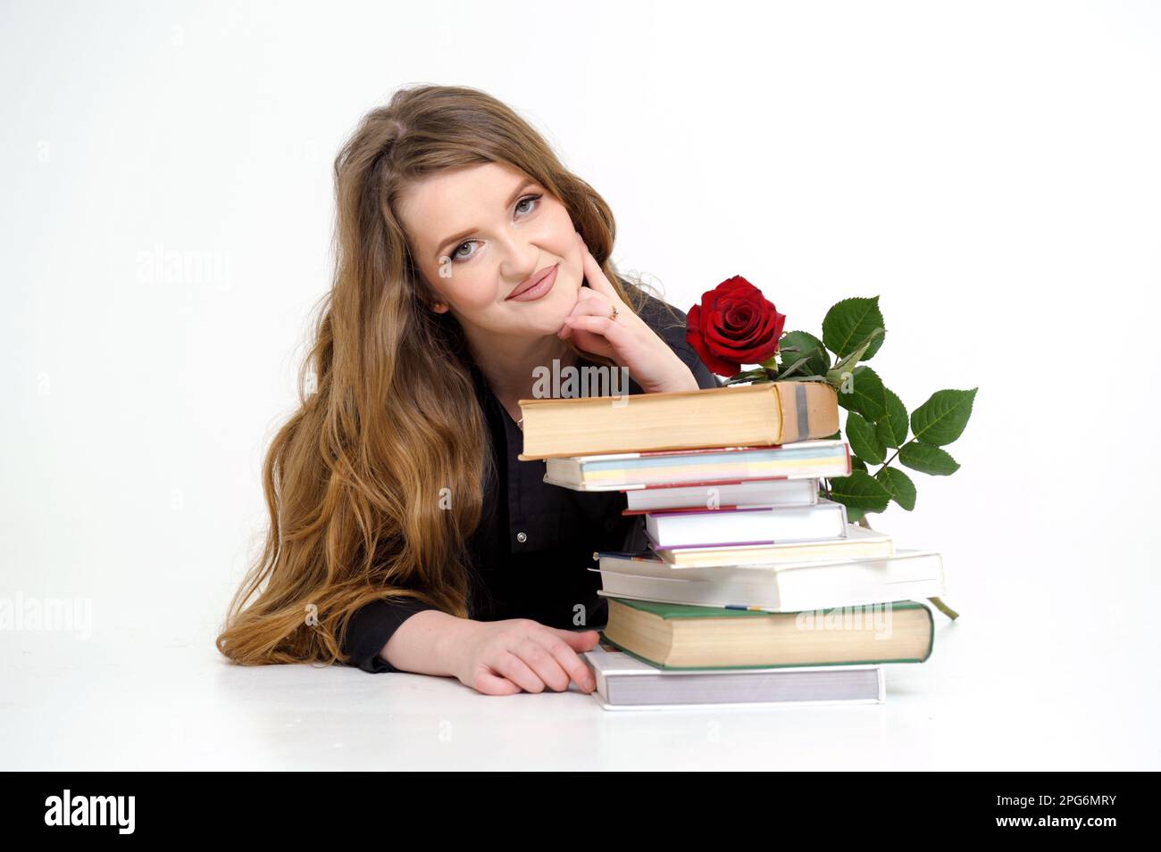 university woman teacher lies on textbooks with rose in her hands sexy  teacher teacher in high heels in black clothes with flowing hair white  background place for text red rose training Come