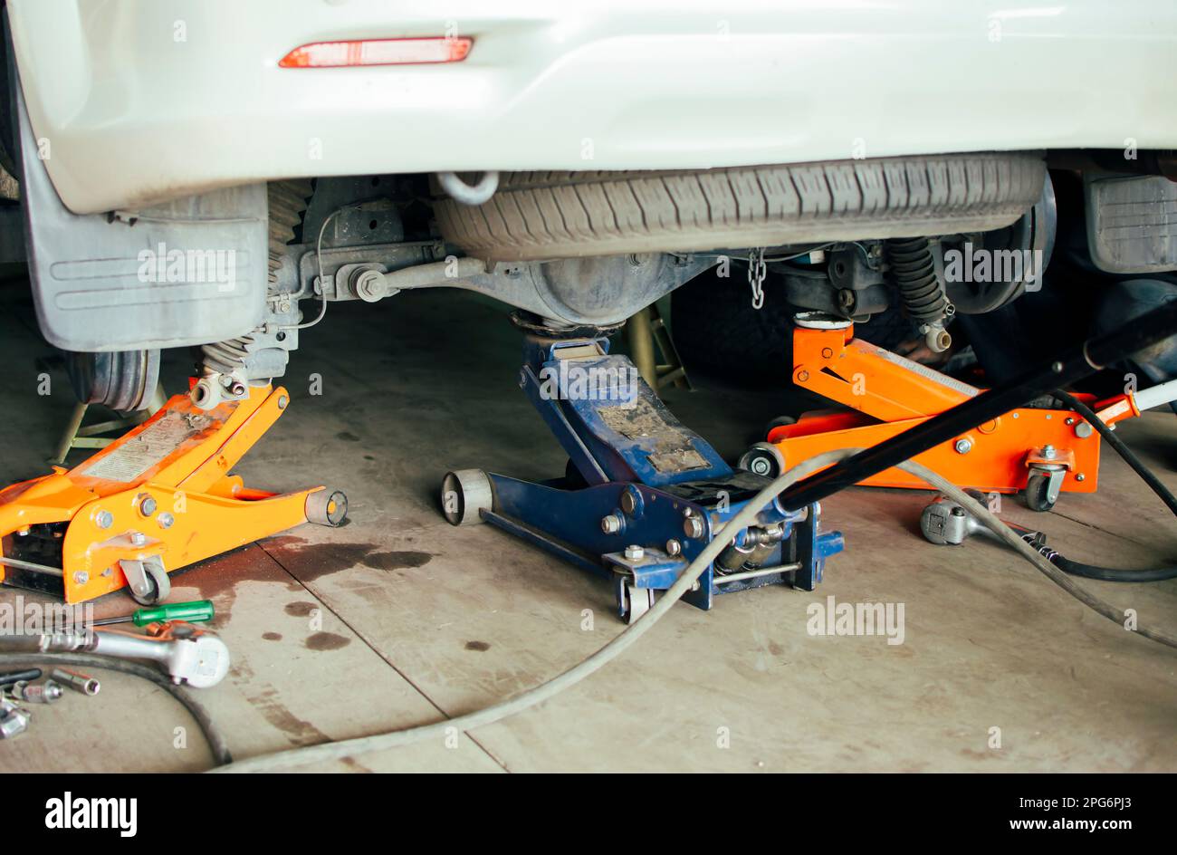 A mechanic lifts a car with three jacks in a auto repair garage to