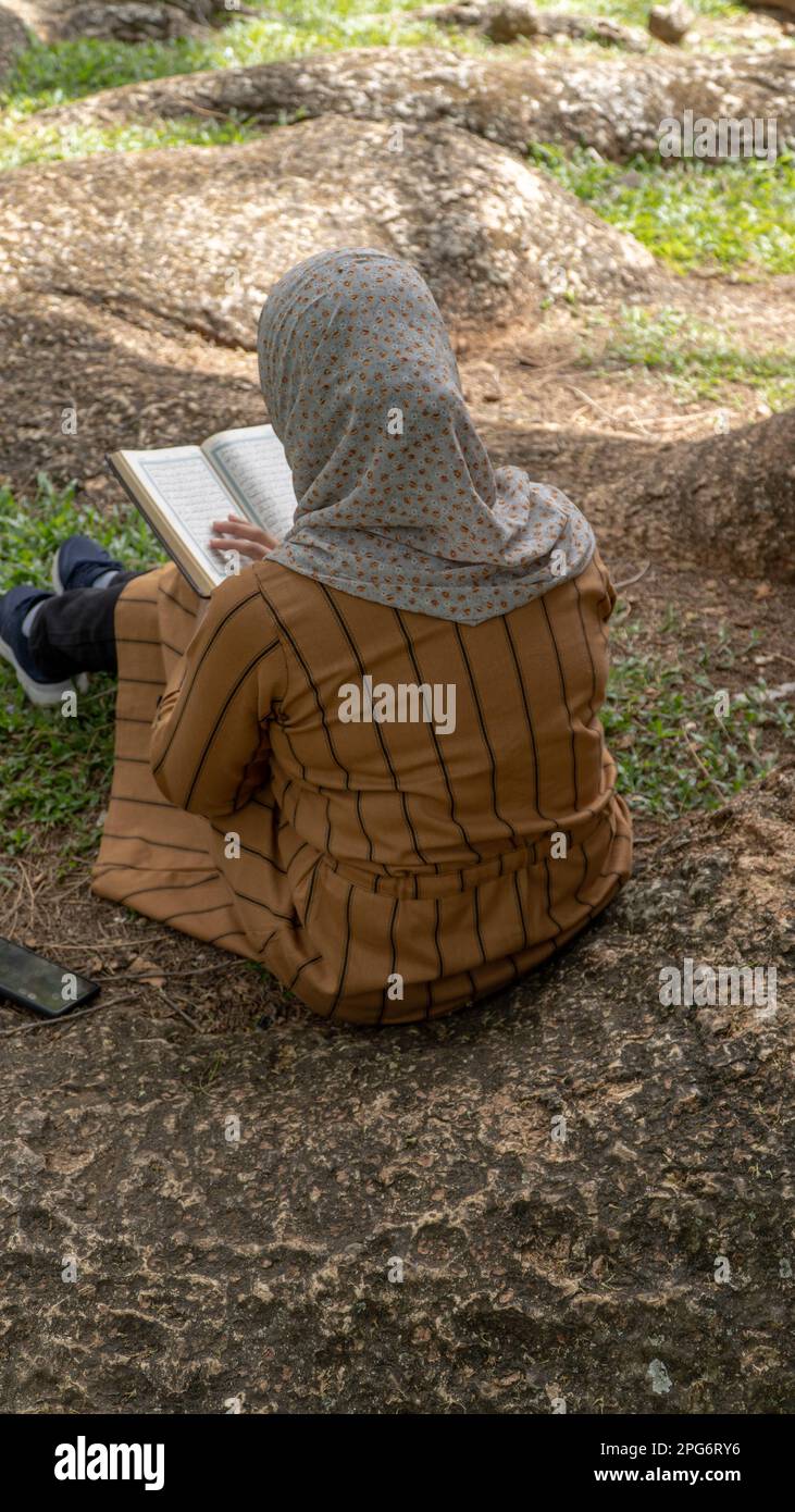 Young muslim woman using a reading book while sitting in the park Stock Photo