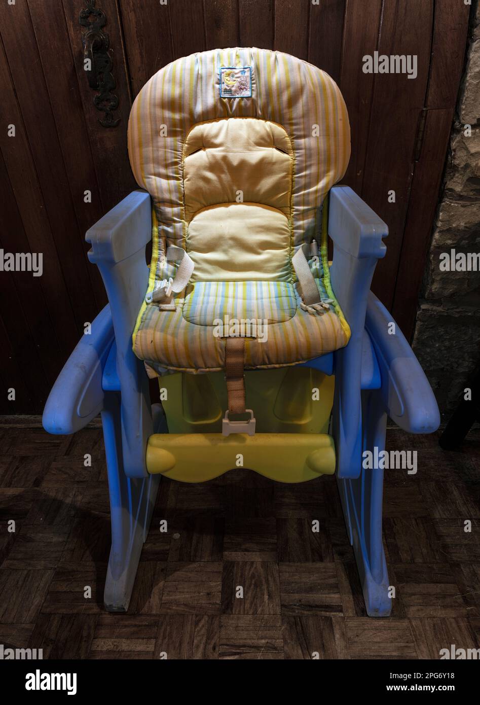 The blue baby-chair with unhappy baby in the Himeville Arms Hotel dining room. Stock Photo