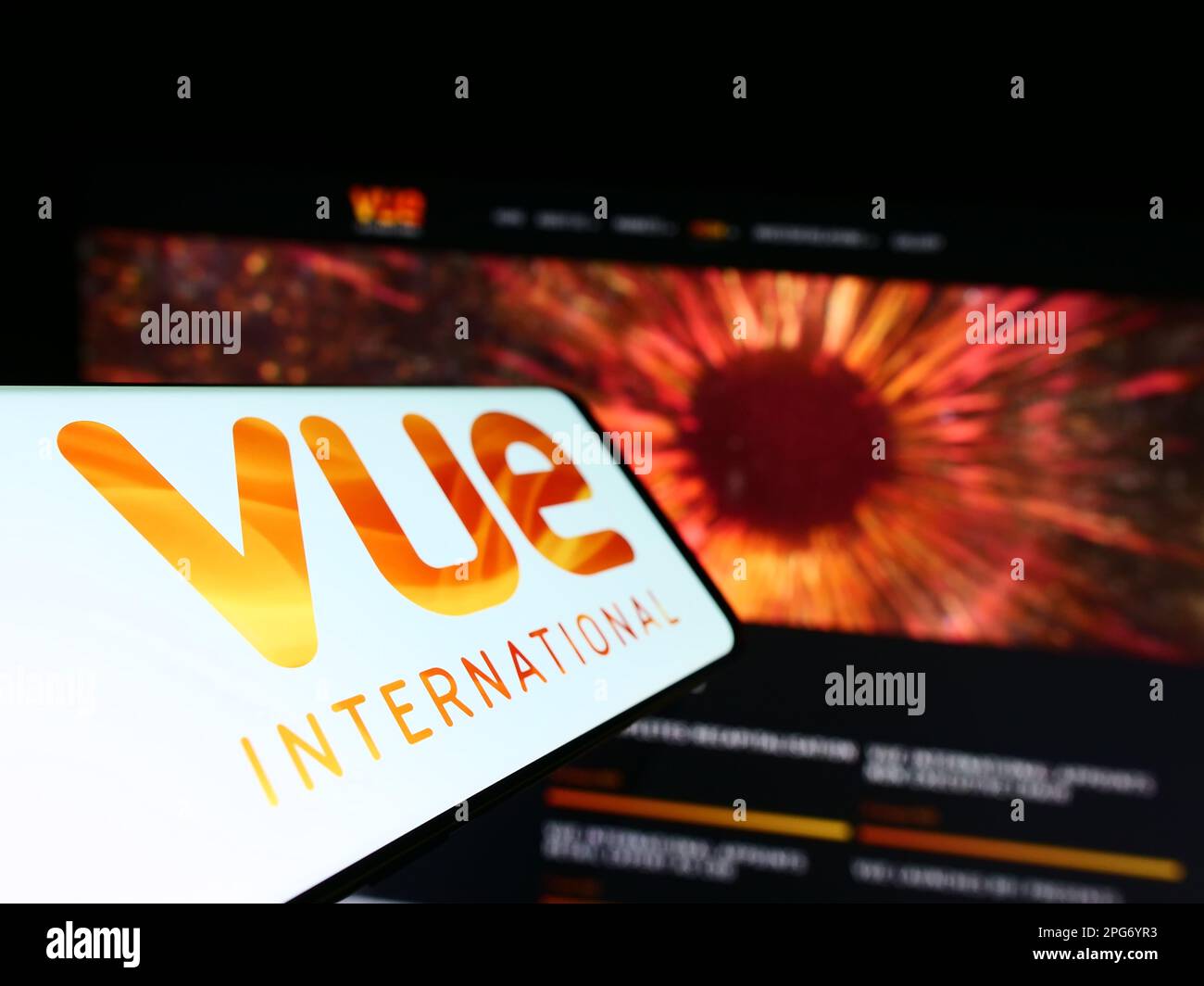 Mobile phone with logo of entertainment company Vue International on screen in front of business website. Focus on center-left of phone display. Stock Photo