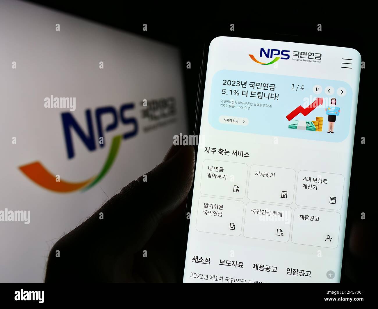 Person holding cellphone with webpage of National Pension Service of Korea (NPS) on screen in front of logo. Focus on center of phone display. Stock Photo