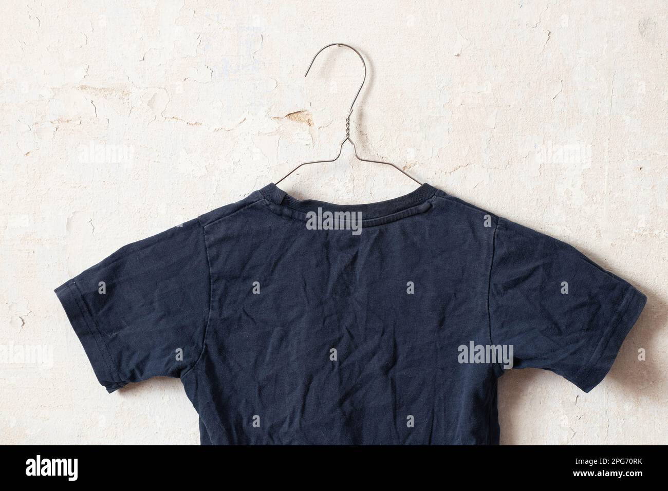 dark blue t-shirt on hangers on an old white wall like moket Stock Photo