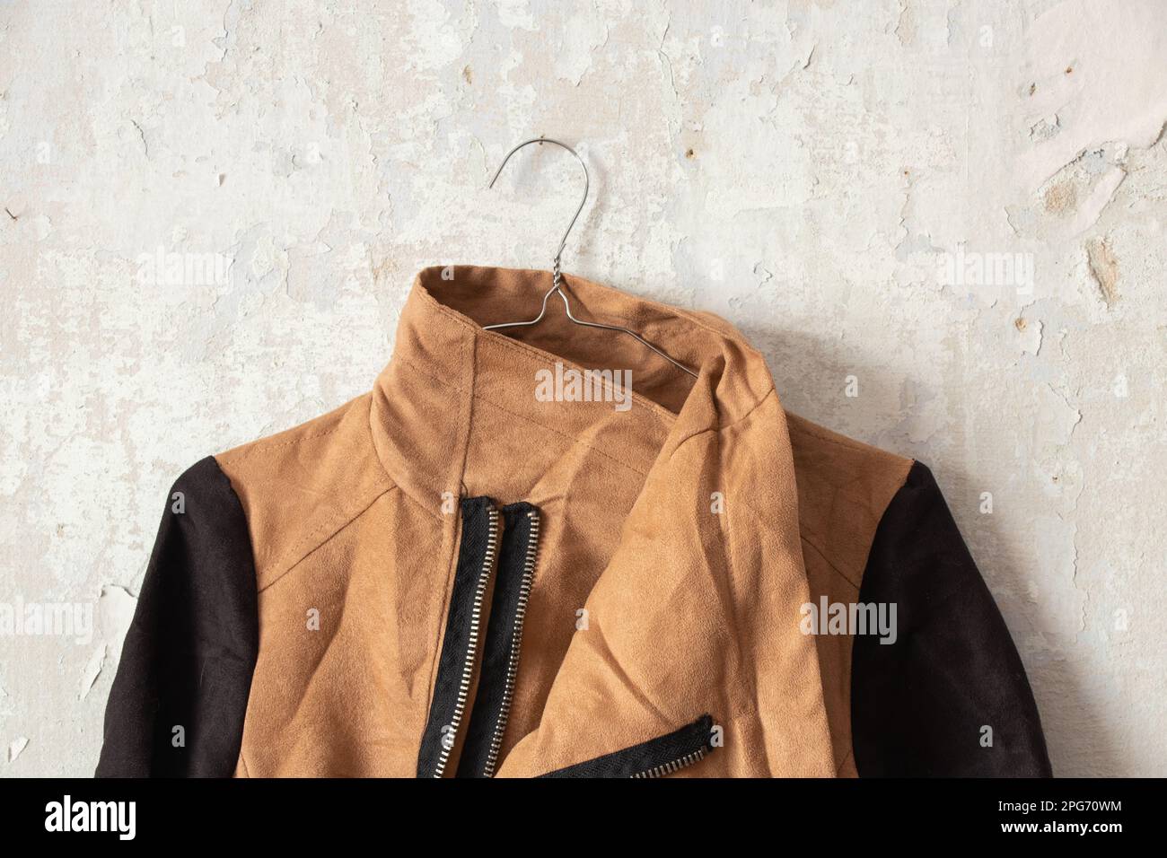 stylish womens brown jacket hanging on white wall at home Stock Photo
