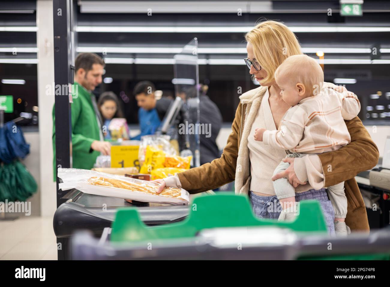 Mother shopping with her infant baby boy, holding the child while