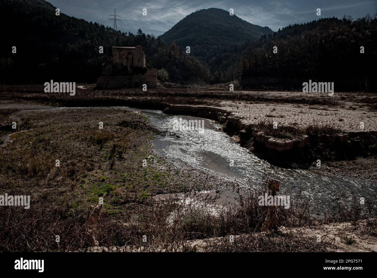 The ancient Romanesque monastery of Sant Salvador de la Vedella, which normally is surrounded by water, is seen at the almost dry riverbed of the Llobregat river while entering the reservoir of La Baells in Cercs, Barcelona Province, Spain. Water restrictions tightened further in Catalonia due to ongoing drought that has now been for 29 months and that is related to climate change and global warming. Currently, Catalan reservoirs are at 27 percent  of their capacity. Stock Photo