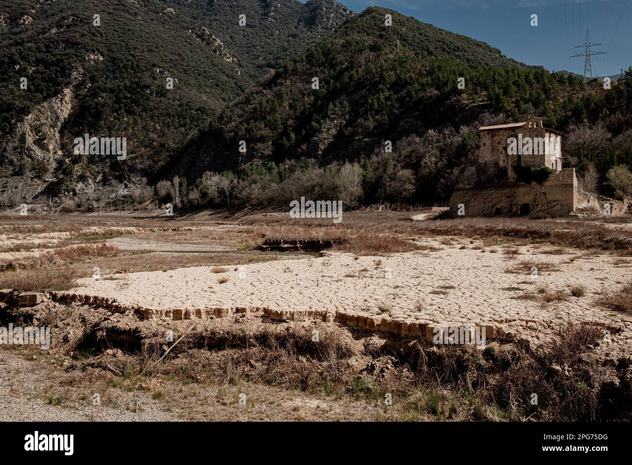 The ancient Romanesque monastery of Sant Salvador de la Vedella, which normally is surrounded by water, is seen at the dry riverbed of the Llobregat river while entering the reservoir of La Baells in Cercs, Barcelona Province, Spain. Water restrictions tightened further in Catalonia due to ongoing drought that has now been for 29 months and that is related to climate change and global warming. Currently, Catalan reservoirs are at 27 percent  of their capacity. Stock Photo