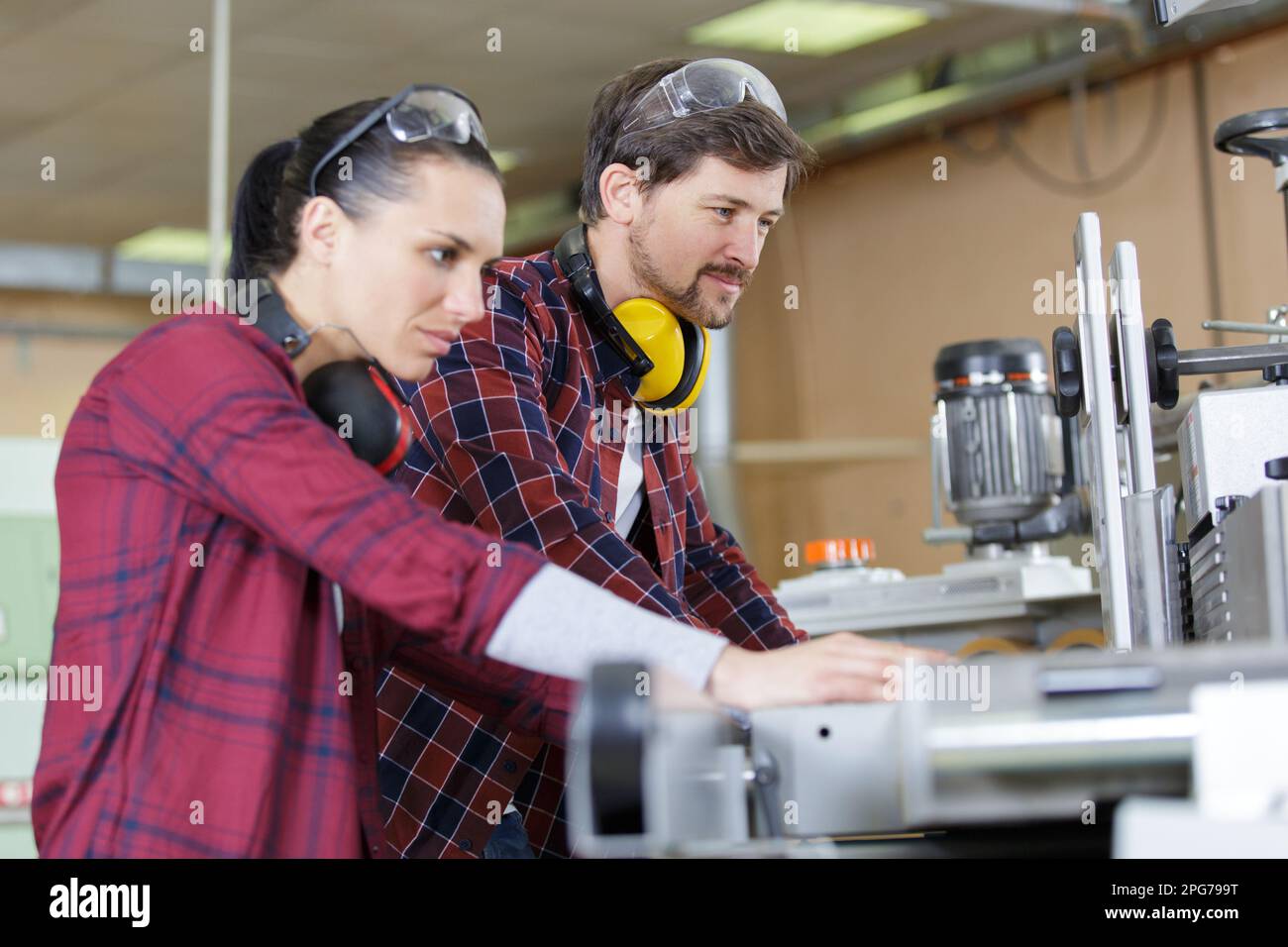 female apprentice working with engineer on cnc machinery Stock Photo