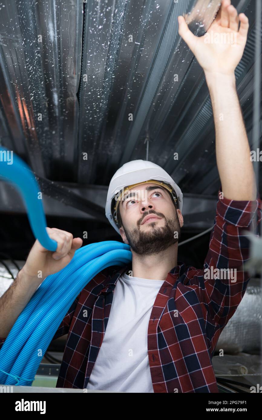 male electrician installing ventilation in ceiling Stock Photo