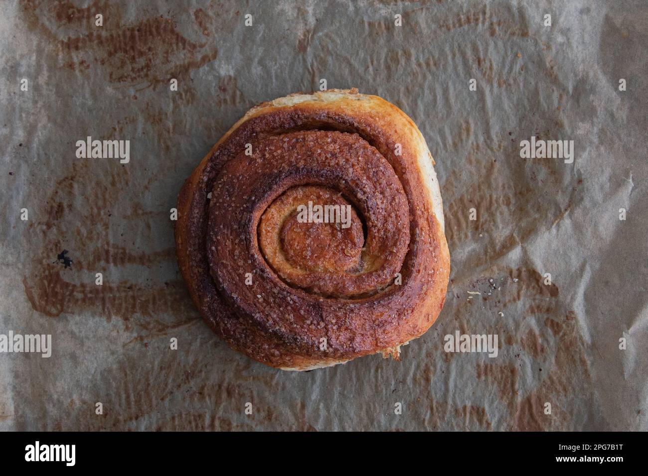 top view of homemade cinnamon bun on sheet of baking paper Stock Photo