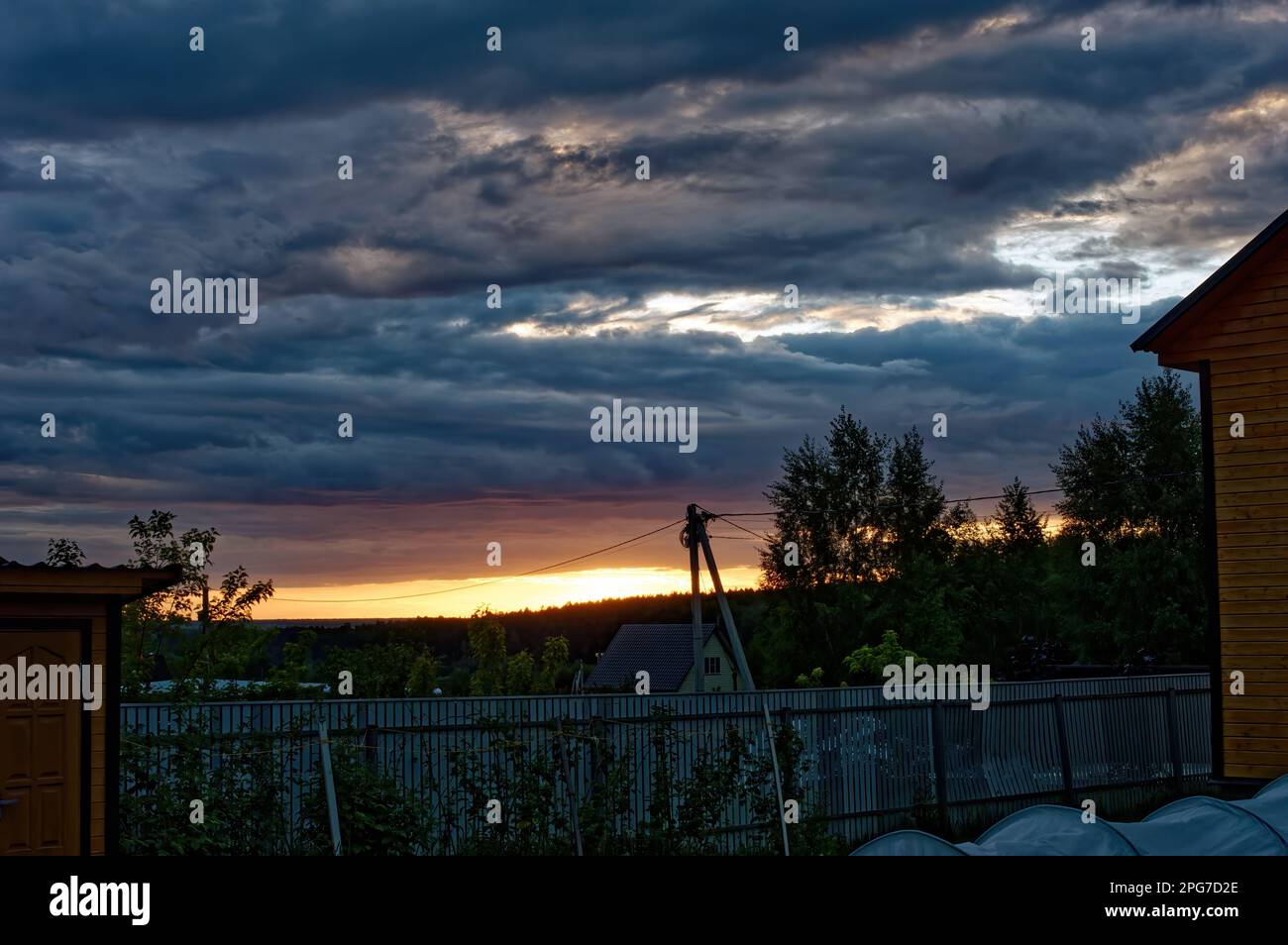 colorful sunset through the clouds in the village, in summer Stock Photo