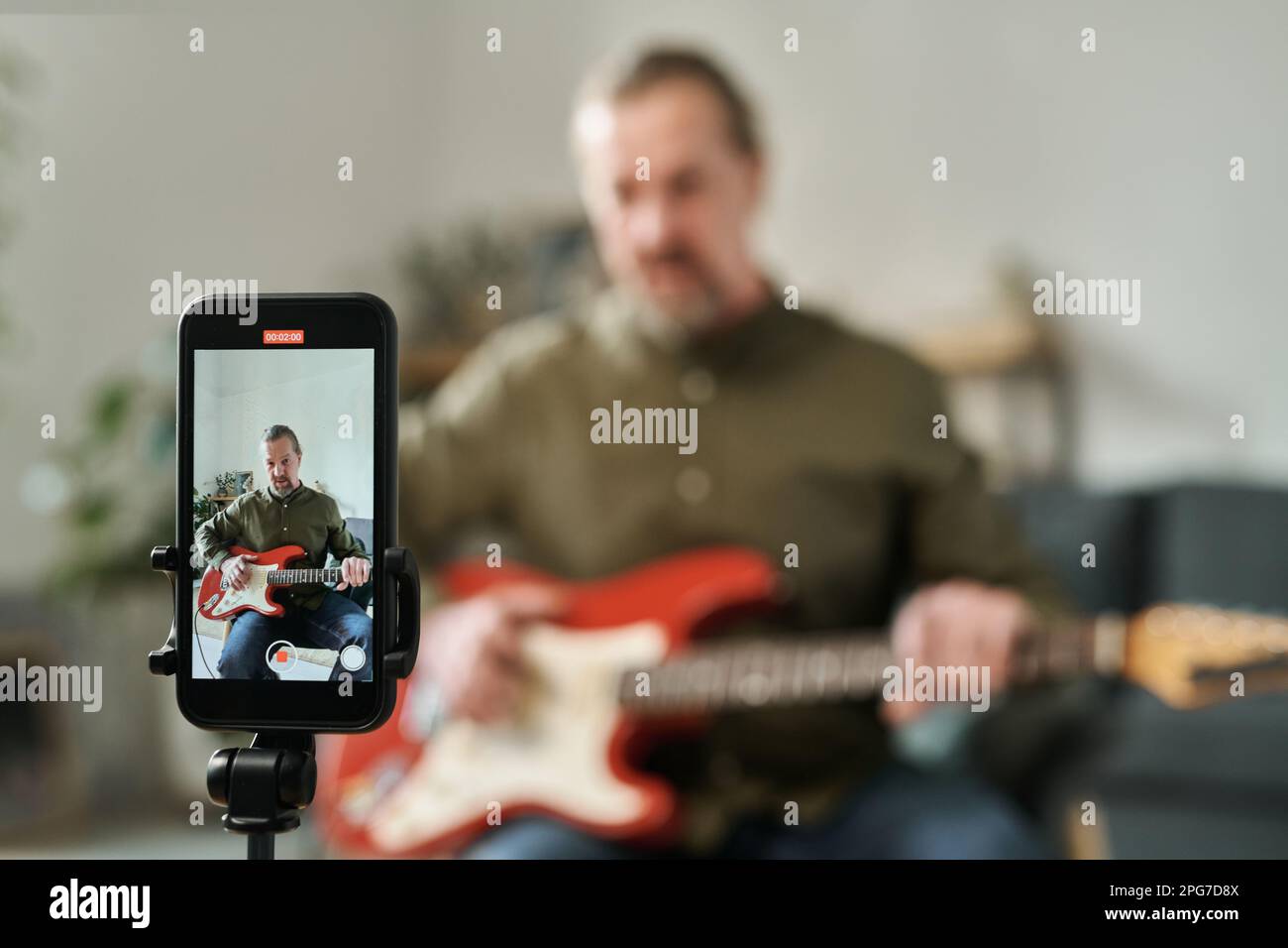 Selective focus of screen of smartphone with guitarist recording online lessons on it at home Stock Photo