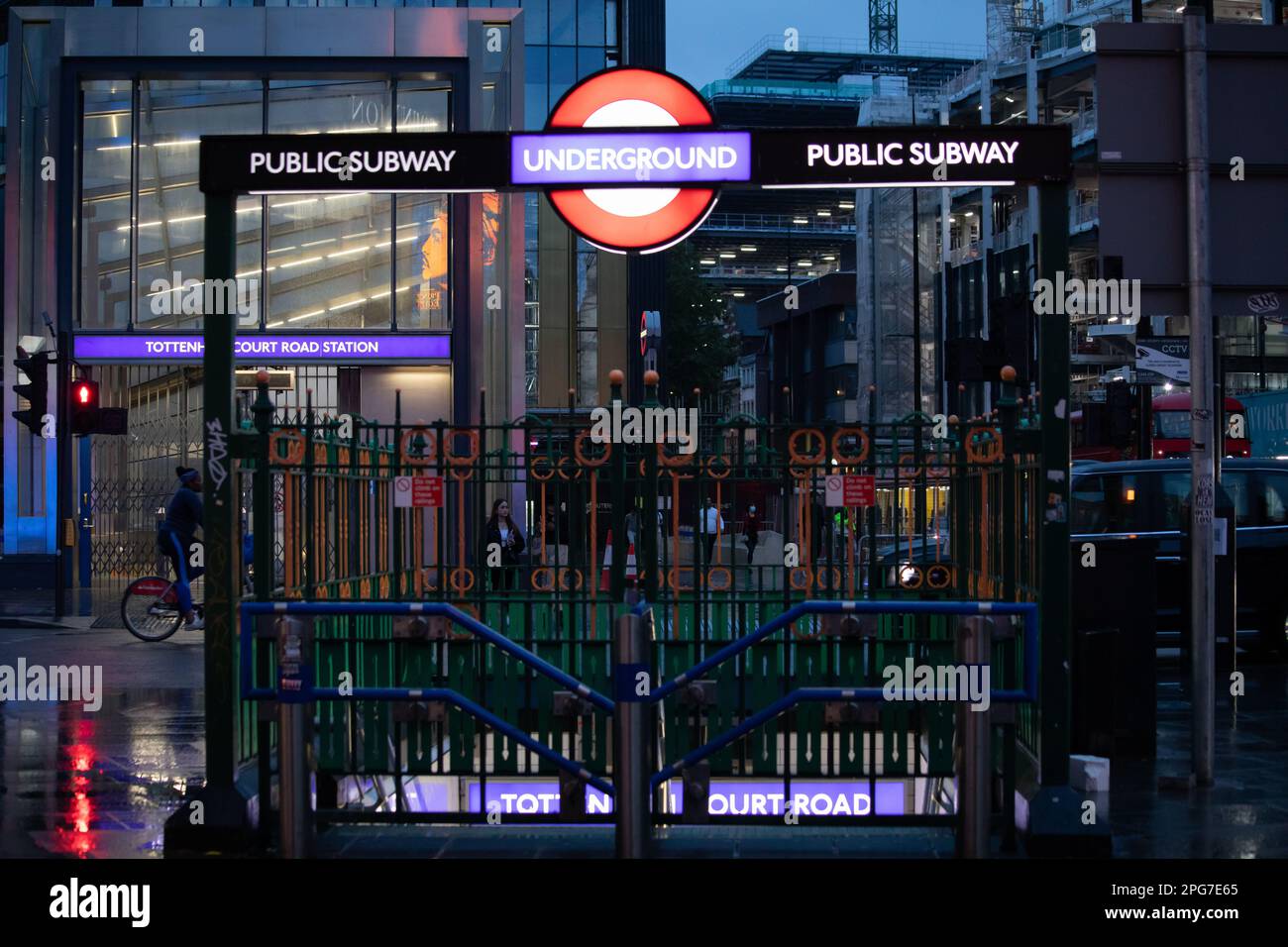 London Underground and Public Subway sign at Tottenham Court Road by night. Busy London street scene with pedestrians, bike, bus, taxi. Stock Photo