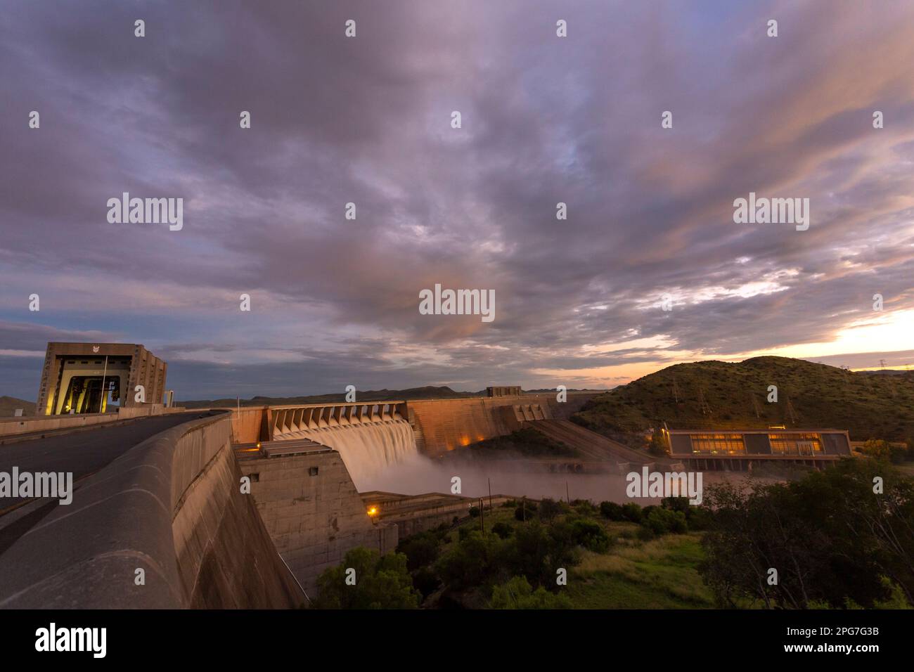 Stock photo of the Gariep Dam wall at dusk with water overflowing and the hydro-electric installation below the dam wall Stock Photo